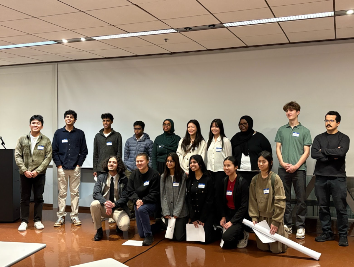 Om S. ‘25 (pictured second from far left) and Henry J. ‘25 (pictured standing and second from far right) pose
with high school students at the concluding symposium for their free twelve-week research program.